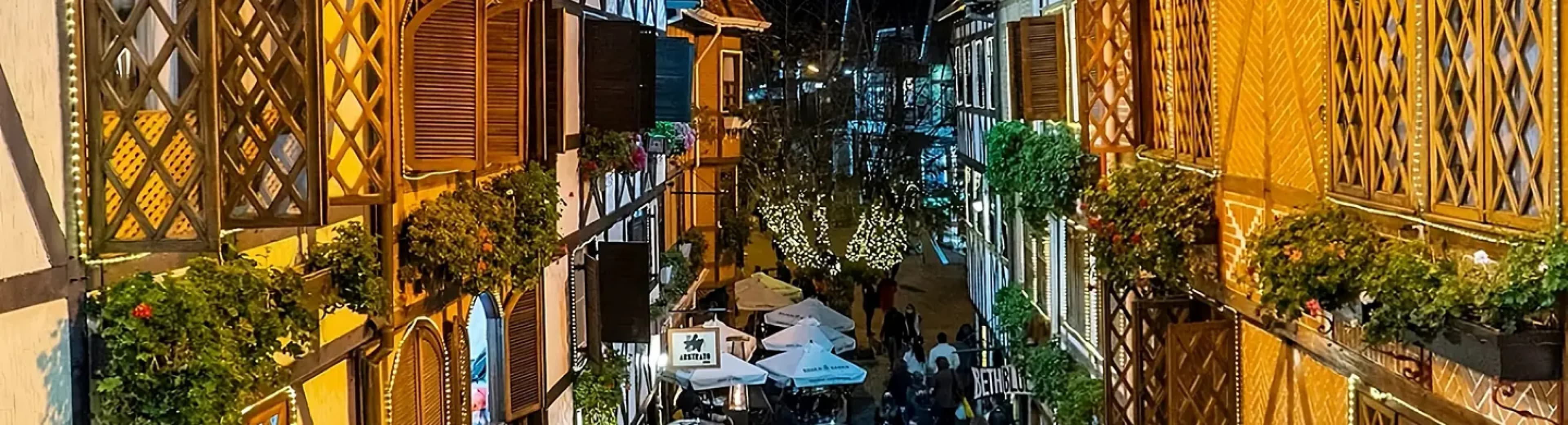 Rua do Capivari iluminada à noite, com lojinhas e movimento