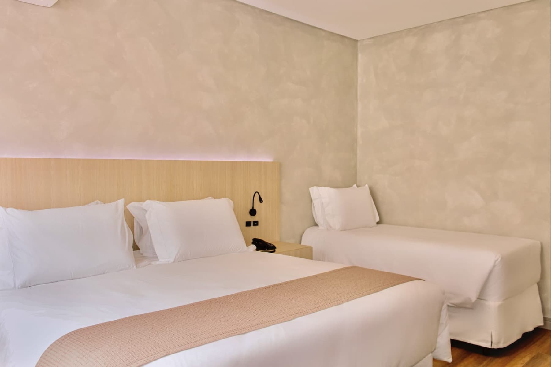 Suíte com cama de casal e solteiro, decoração aconchegante em tons terrosos